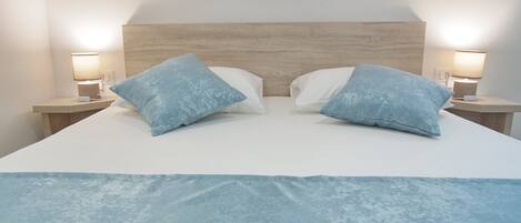 A bed with a wooden headboard, two nightstands with lamps, and two pillows.