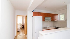 Una cocina moderna con armarios blancos, un refrigerador, un microondas y un lavamanos.