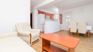 Una sala de estar moderna con un sofá, una mesa de centro de madera y una zona de comedor con sillas y una mesa.