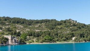 A coastal view with a historic building near the water, surrounded by dense greenery and hills. - Dream 2BR apartment6#Mljet#seaview (Mljet)