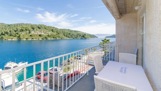 Ein Balkon mit Blick auf einen See, Boote und eine entfernte Hügelkette.