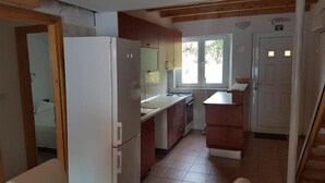 Een kleine keuken met een koelkast, een spoelbak en houten kastjes.