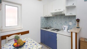 Una cocina compacta con armarios azules, salpicadero de azulejos y una encimera pequeña.