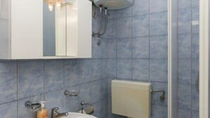 Un baño con lavamanos, inodoro y zona de ducha.