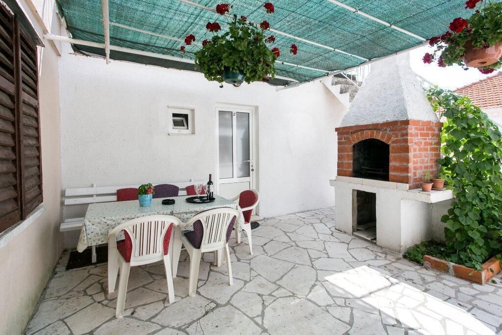 Un patio al aire libre con un horno de ladrillo, paredes blancas y una mesa con sillas.
