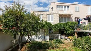 Un barrio residencial con jardín, un balcón con ropa tendida y un edificio con balcón y ventanas.