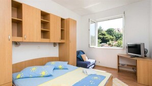 Un dormitorio con dos camas, televisión y ventana con vistas a zonas verdes.