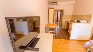 Un espacio habitable compacto con televisión de pantalla plana, un pequeño comedor y una kitchenette.
