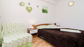 Une chambre à coucher comprenant un lit, une chaise, une table de chevet et un mur décoré de différents objets.