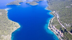 Vue aérienne d’une zone côtière comprenant une vaste étendue d’eau, plusieurs petites îles et une côte densément végétalisée.