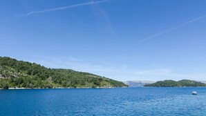 Un lac paisible avec une petite barque, entouré de collines verdoyantes et sous un ciel dégagé.