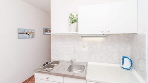 Una cocina moderna con armarios blancos, un lavamanos de acero inoxidable y una tetera.