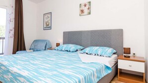 Un dormitorio con cama, mesita de noche, una silla y obras de arte en la pared.