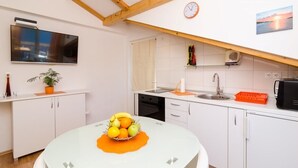 A modern kitchen with white cabinets, a dining table with a fruit bowl, a clock, and a view of the sunset. - Corso turquoise view, 1BR APT with balcony and sea view (Mljet)