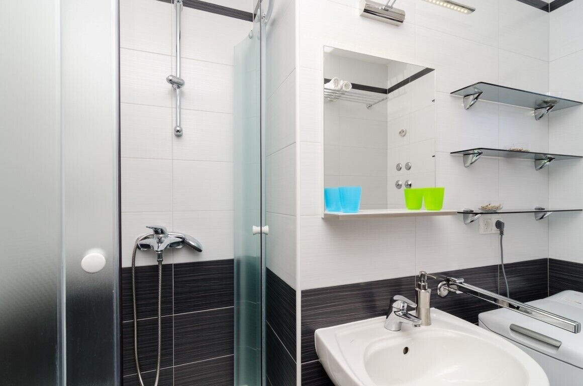 A modern bathroom with a glass shower enclosure, a white sink, and chrome fixtures.