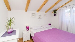 A bedroom with a bed, bedside tables, a nightstand, a potted plant, and a window with curtains. - Corso turquoise view, 1BR APT with balcony and sea view (Mljet)