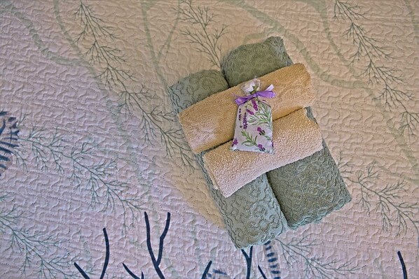 A bed with a textured blanket and a decorative pillow with a floral pattern.