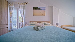Une chambre à coucher avec un lit, une vue sur la plage et une fenêtre avec des rideaux.