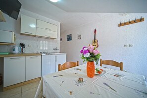 Une cuisine compacte avec des meubles blancs, un petit réfrigérateur et un coin repas avec une table dressée pour deux personnes.