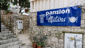 Un bâtiment en pierre sur lequel est accrochée une banderole bleue avec l’inscription « Pension Matana 101 ».