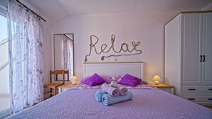 Une chambre à coucher avec un lit, des oreillers, une table de chevet, une chaise, une armoire et un mur sur lequel est écrit le mot «Détendez-vous».
