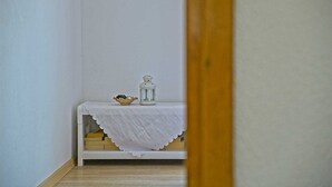 Un couloir étroit, avec une table blanche au fond, sur laquelle sont posés une lanterne blanche et un petit bol.