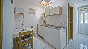 Une cuisine compacte avec un coin repas, comprenant un four encastré, un évier et une petite table avec des chaises.