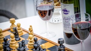 A chessboard, a bottle of wine, and glasses on a table.