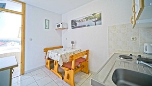A small kitchen with a wooden table and bench, a microwave, and a sink.