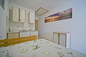 Cozy retreat with a bed, kitchenette, and dining table for two.