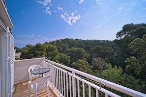 Relax on the balcony with a serene view of the lush forested hillside, perfect for dining or unwinding.