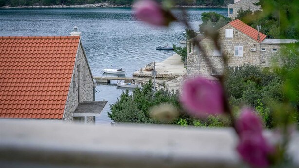 Un pueblo costero con edificios de piedra, un muelle con barcos y vistas al mar.
