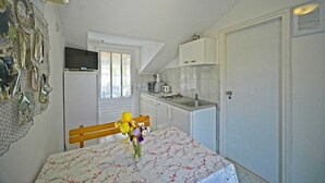 Eine kleine Küche mit Essbereich, einem an der Wand befestigten Fernseher und einer Tür zu einem weiteren Raum.