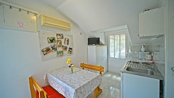 Een koelkast, een magnetron, een kookplaat, kookgerei, borden en bestek