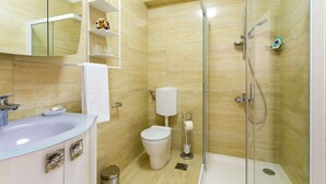 A modern bathroom with a glass-enclosed shower, a white sink, and a toilet.