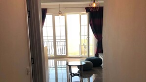 A hallway leading to a living area with a glass door, a ceiling light fixture, and a view of the outdoors.