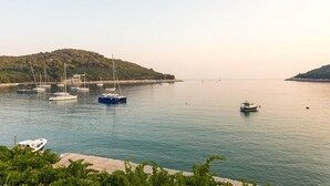 A calm harbor with several boats docked, a hilly landscape in the background, and a clear sky.