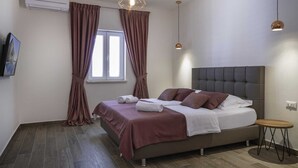 A modern bedroom with a large bed, a small table, and a window with curtains. - Jasmin Lush TOP FLOOR - one bedroom apartment (Mljet)