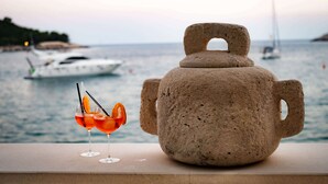 A stone urn on a ledge with a view of the sea and boats in the background. - Jasmin Lush TOP FLOOR - one bedroom apartment (Mljet)