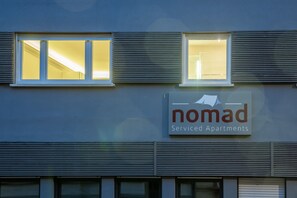 A building with a sign that reads "nomad Service Apartments."