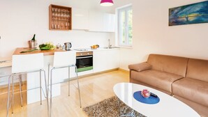 Una cocina moderna con armarios blancos, una botellera de madera y una lámpara colgante rosa.