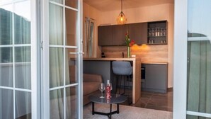 Een moderne keuken met een eetgedeelte, een glazen deur naar buiten en een hangende lamp.