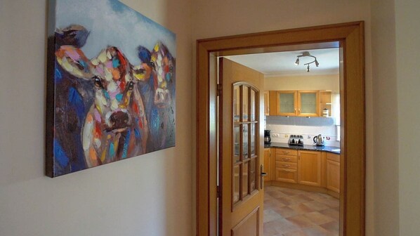A hallway leading to a kitchen with wooden cabinets and a tiled floor.