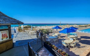 A beachside patio with outdoor seating and a view of the ocean.
