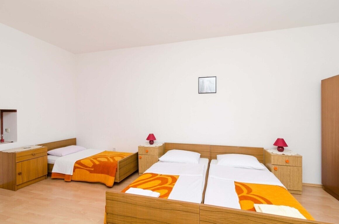 A hotel room with two single beds, wooden nightstands with lamps, and a small wall-mounted picture.