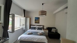 A bedroom with a bed, bedside tables, a chair, a window, and a hanging light fixture.