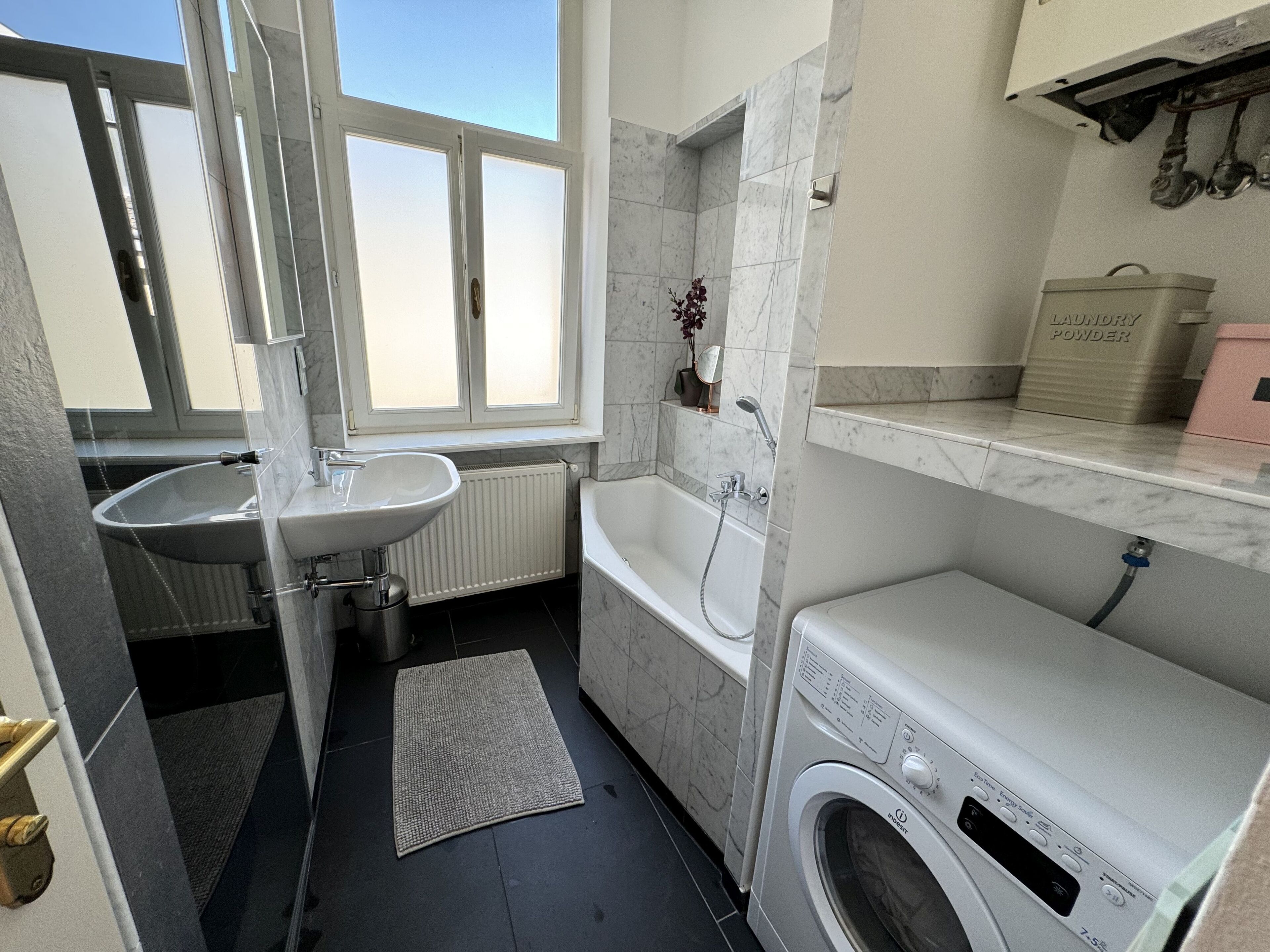 Ein kleines Badezimmer mit Waschbecken, Badewanne und Waschmaschine.