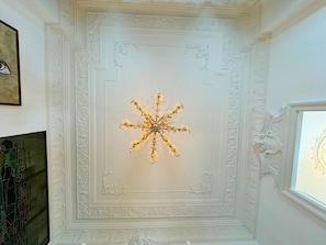 A chandelier with a star-shaped design in a room with ornate white walls and a decorative ceiling.