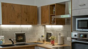 Una cucina moderna con mobili in legno, un lavello in acciaio inossidabile, un forno a incasso e un microonde.