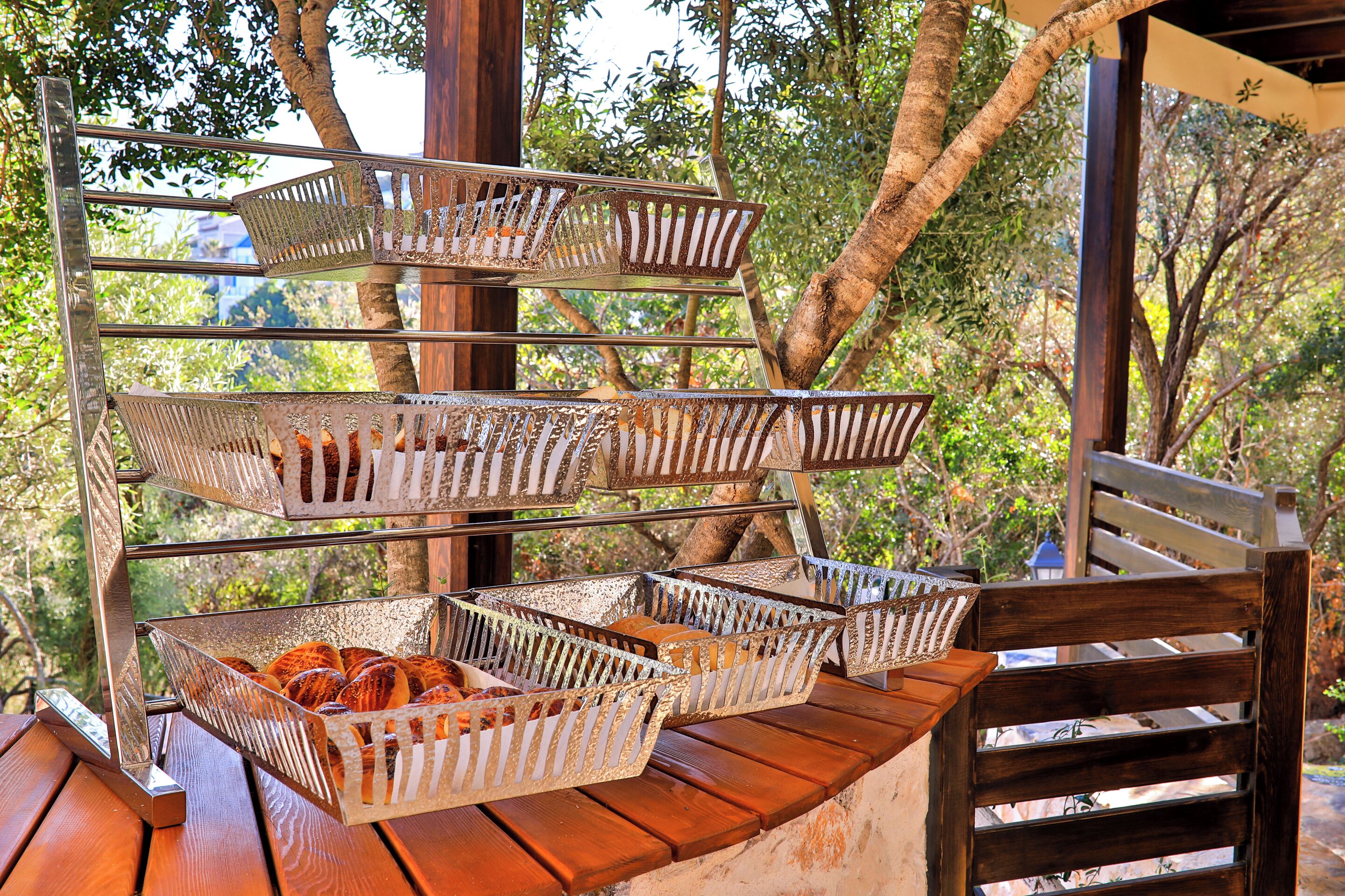 A wooden bench with metal baskets containing bread.